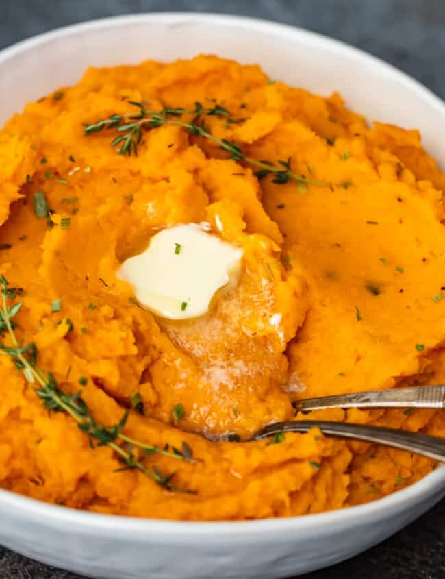 Savory mashed sweet potatoes with sprigs of thyme.