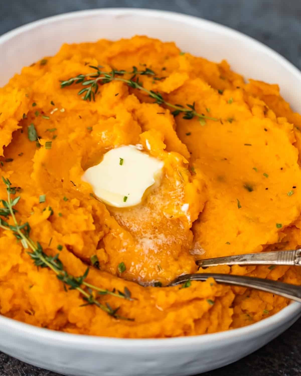 Savory mashed sweet potatoes with sprigs of thyme.