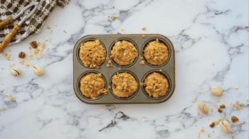 Breakfast muffins in a muffin tin on a marble countertop.
