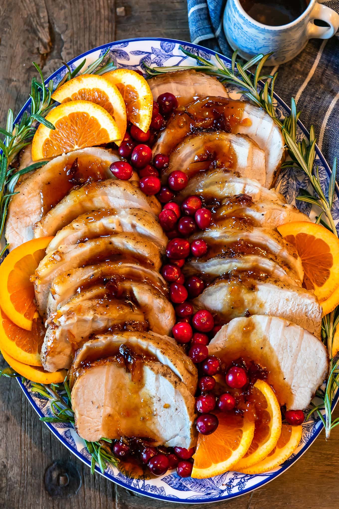 overhead view of a plate of roasted pork, topped with cranberries and orange slices