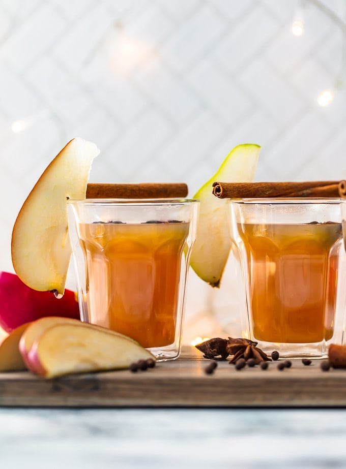 two glasses of pear cider garnished with sliced apples and pears