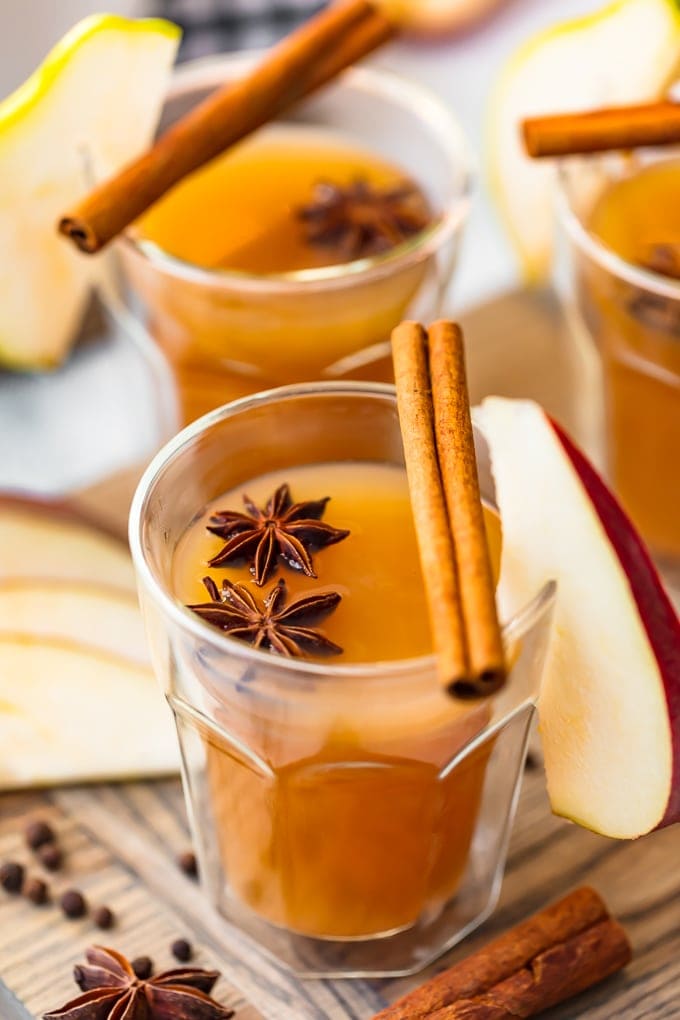 glasses of fall spiced pear cider in a short glass, with whole spices and apple slices as garnish.