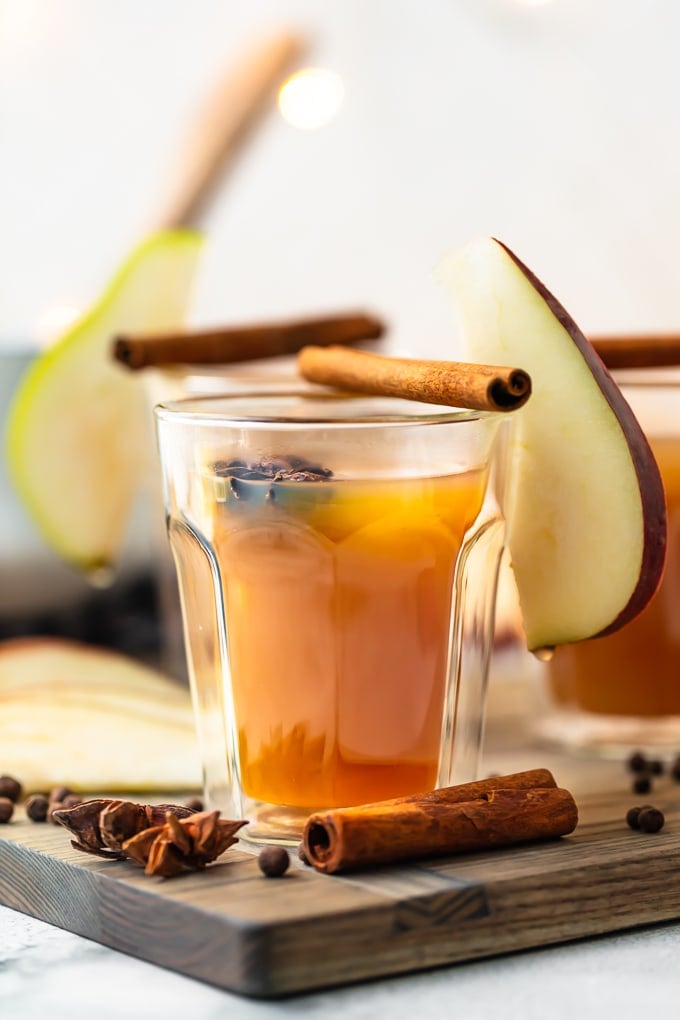 a glass of ginger pear cider, garnished with cinnamon sticks