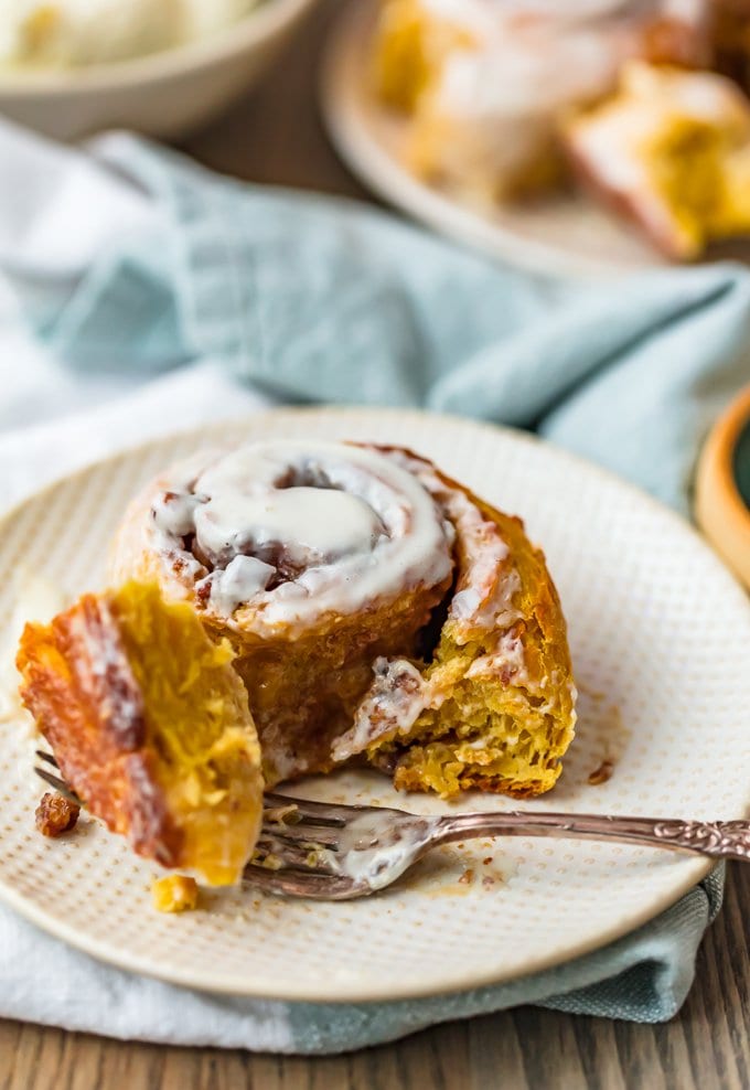 a pumpkin cinnamon roll on a small white plate