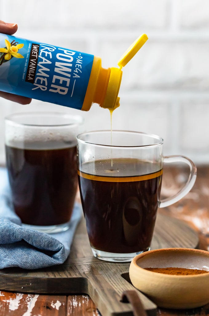 pouring creamer into a cup of coffee