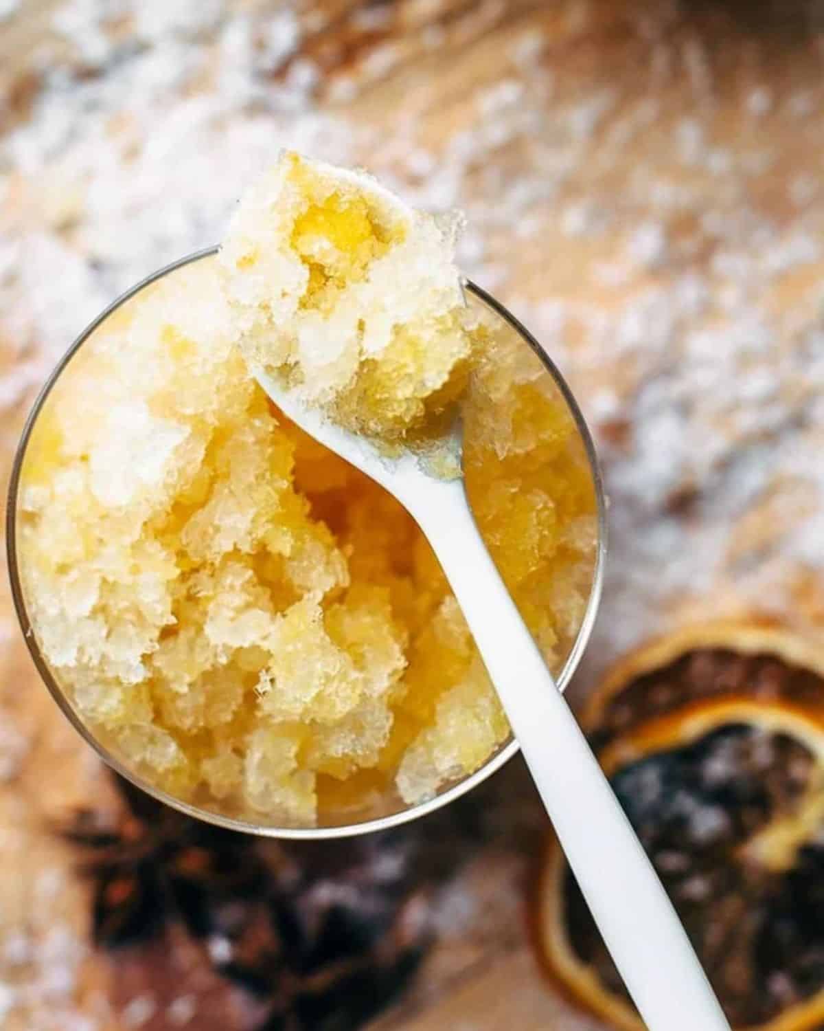 This Bourbon Slush cocktail drink is loved by all who come to my house on Christmas Eve. We have this Orange Bourbon Slush every year and it's such a fun and easy drink recipe, you have no reason not to try it! A spoon with orange bourbon slushie on it.