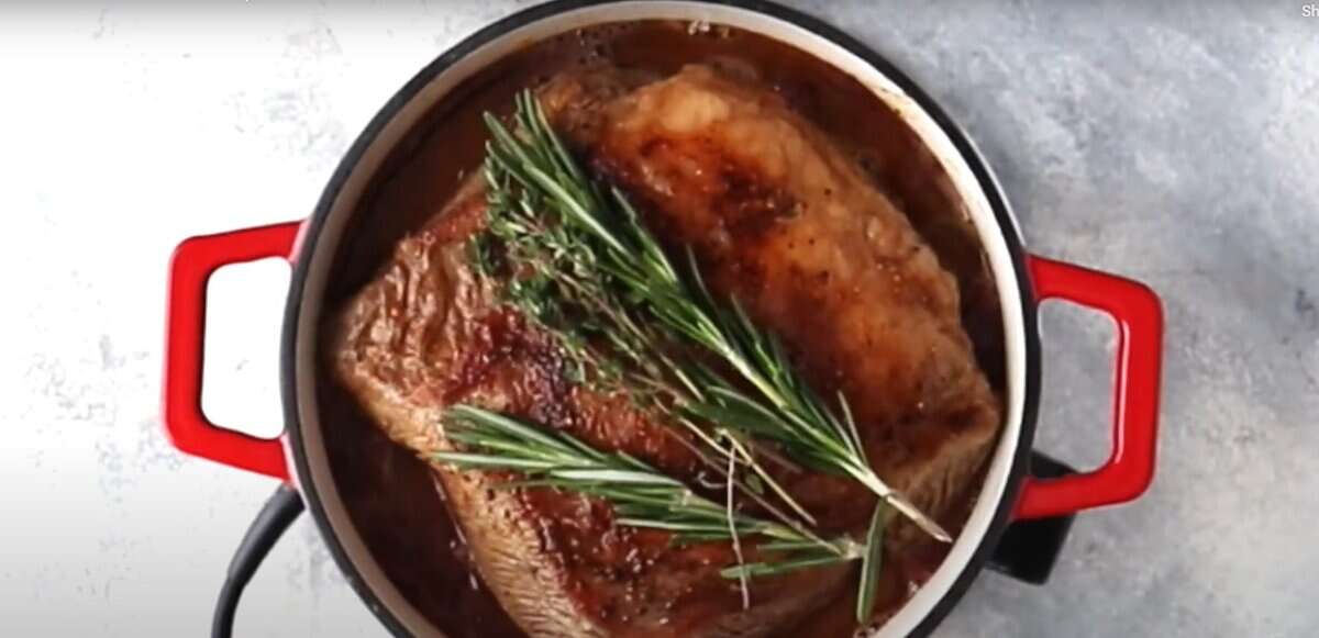 Pot roast over the caramelized vegetables with rosemary sprigs on top. 