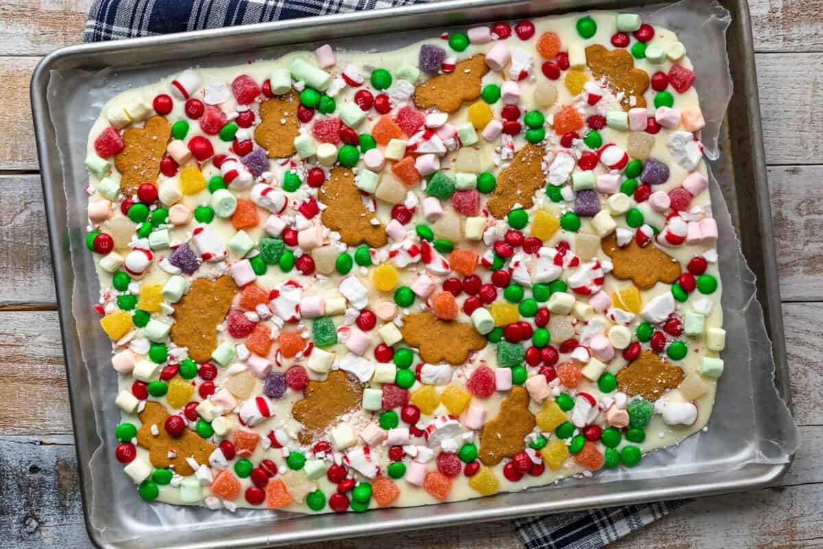 Gingerbread House White Chocolate Bark is a fun and festive Christmas Bark sprinkled with marshmallows, soft peppermints, gumdrops, M&Ms, and of course ginger cookies! This Gingerbread House Bark Recipe has all the flavors you might find on a classic gingerbread house, but with none of the fuss.