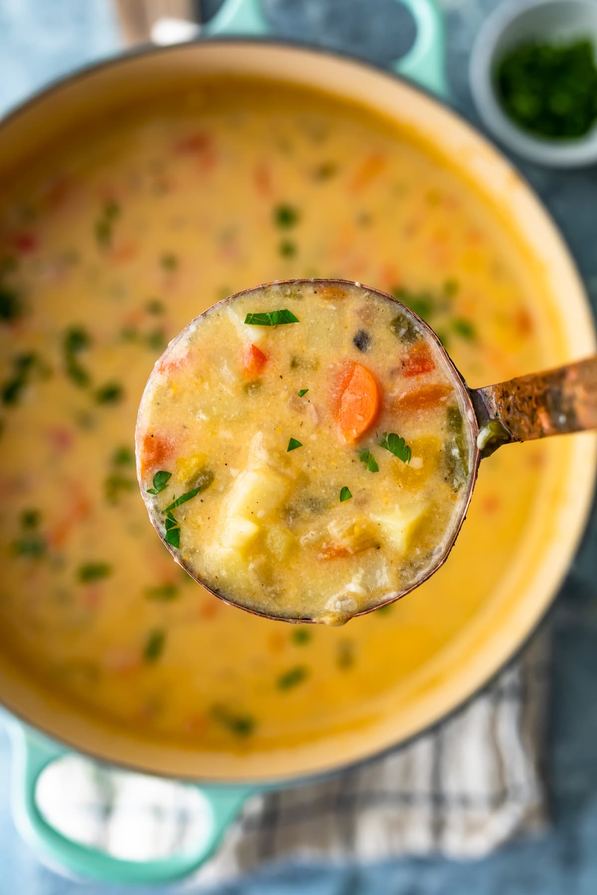 a pot of cheesy potato chowder, with a ladle of soup held above it