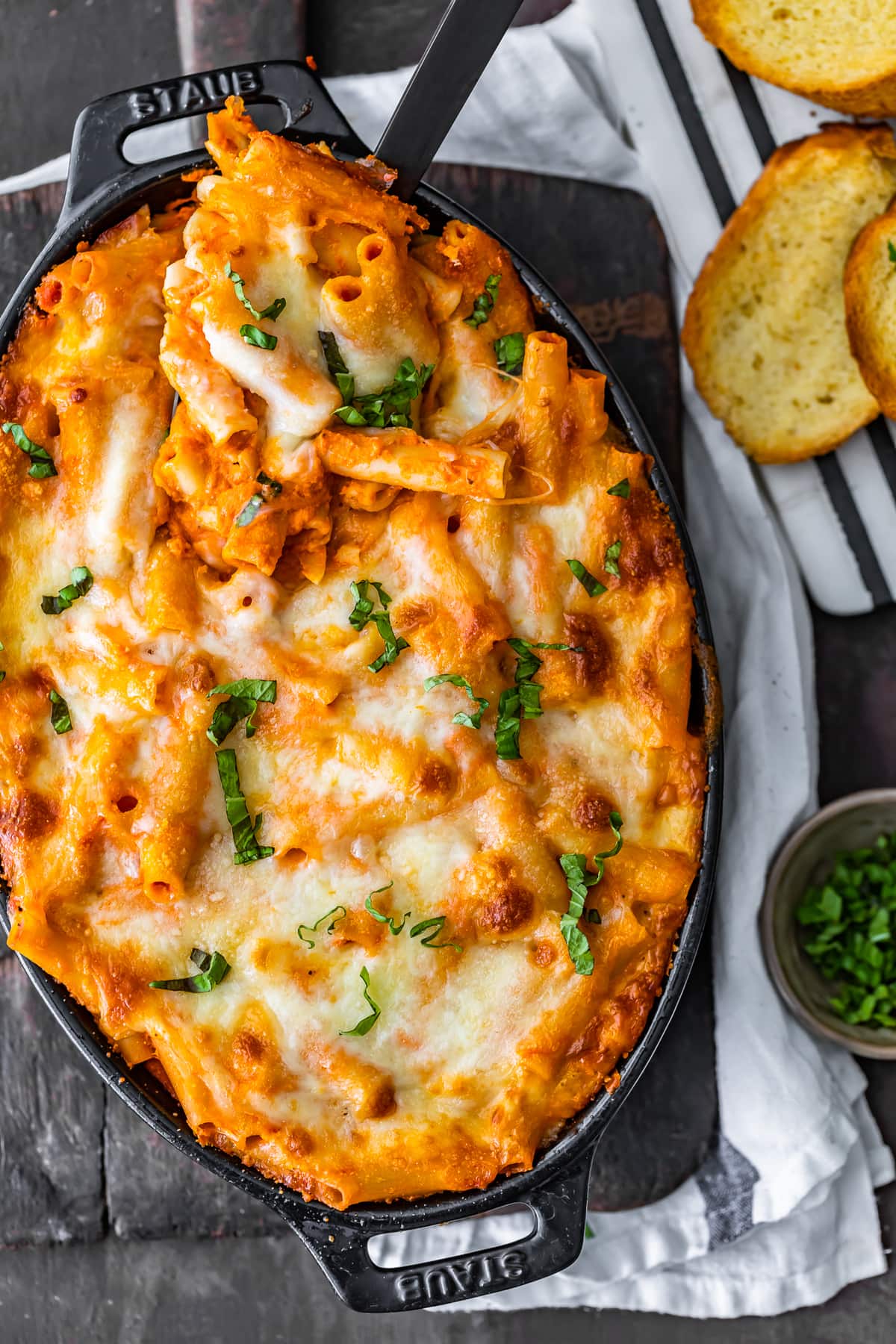 the best baked ziti recipe in a casserole dish, next to slices of bread 
