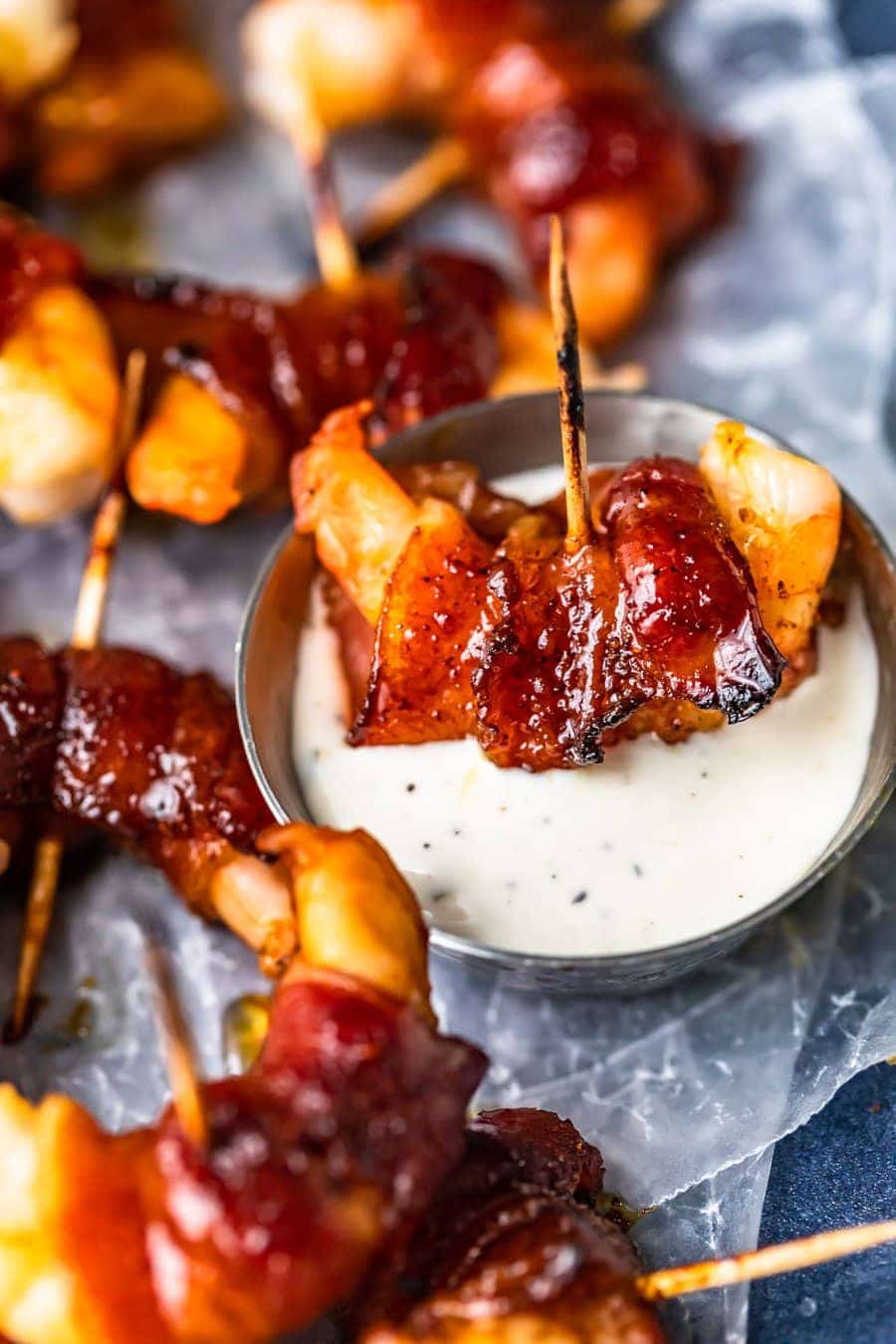 close up on a bacon wrapped shrimp dipped in a small bowl of ranch