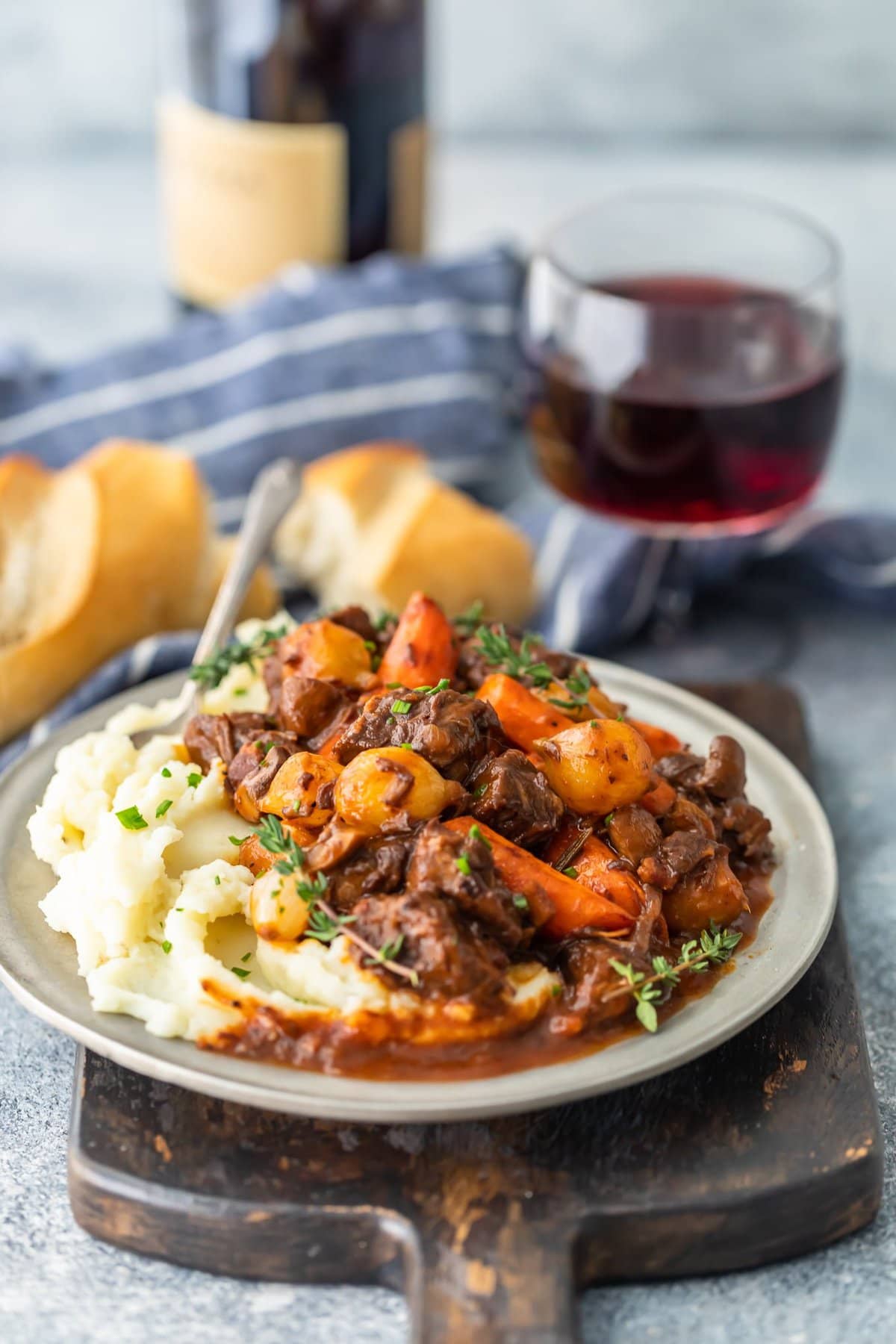 a plate of boeuf bourguignon next to a glass of red wine