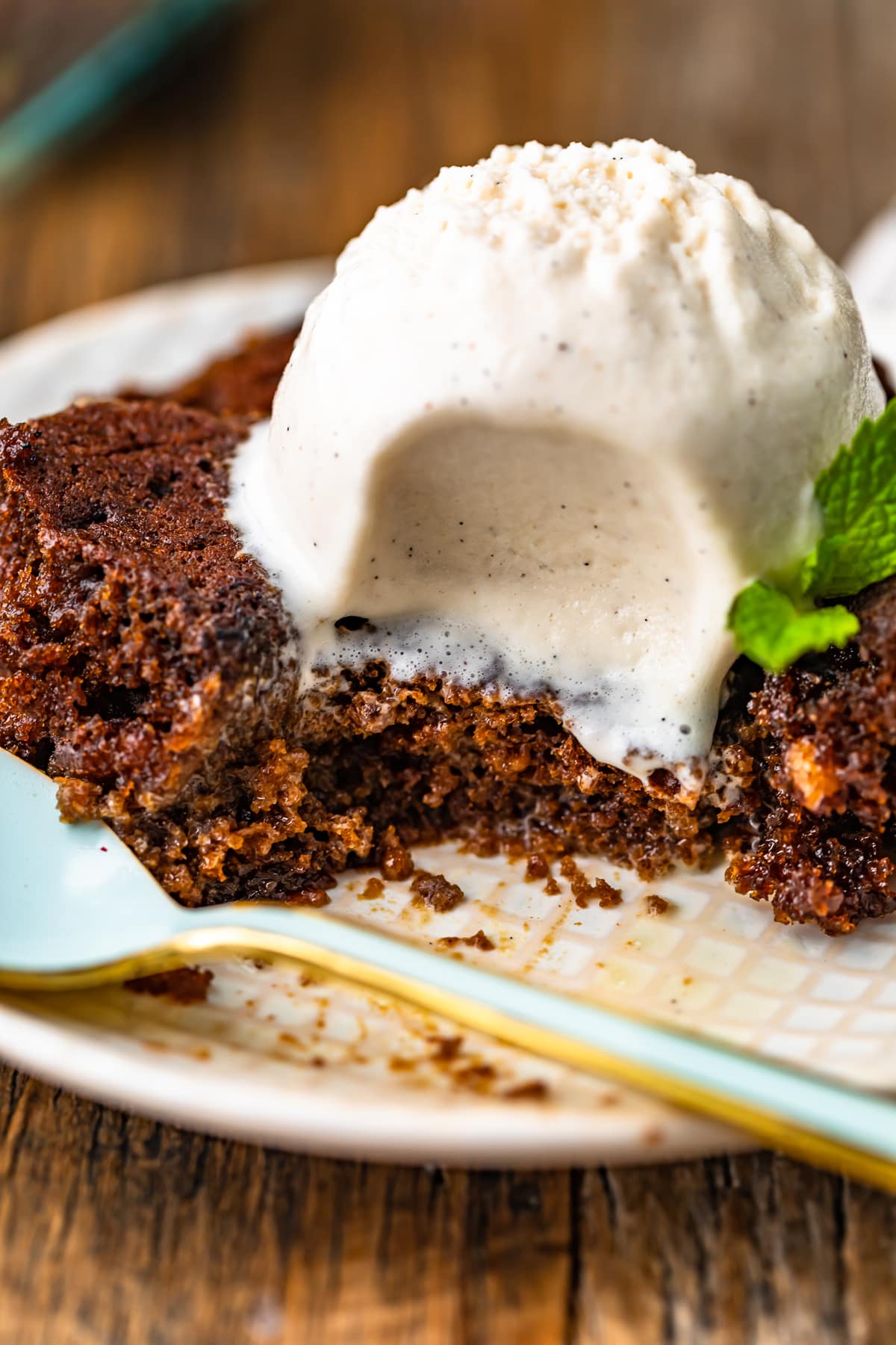 side view of gingerbread pudding cake and vanilla ice cream on a plate