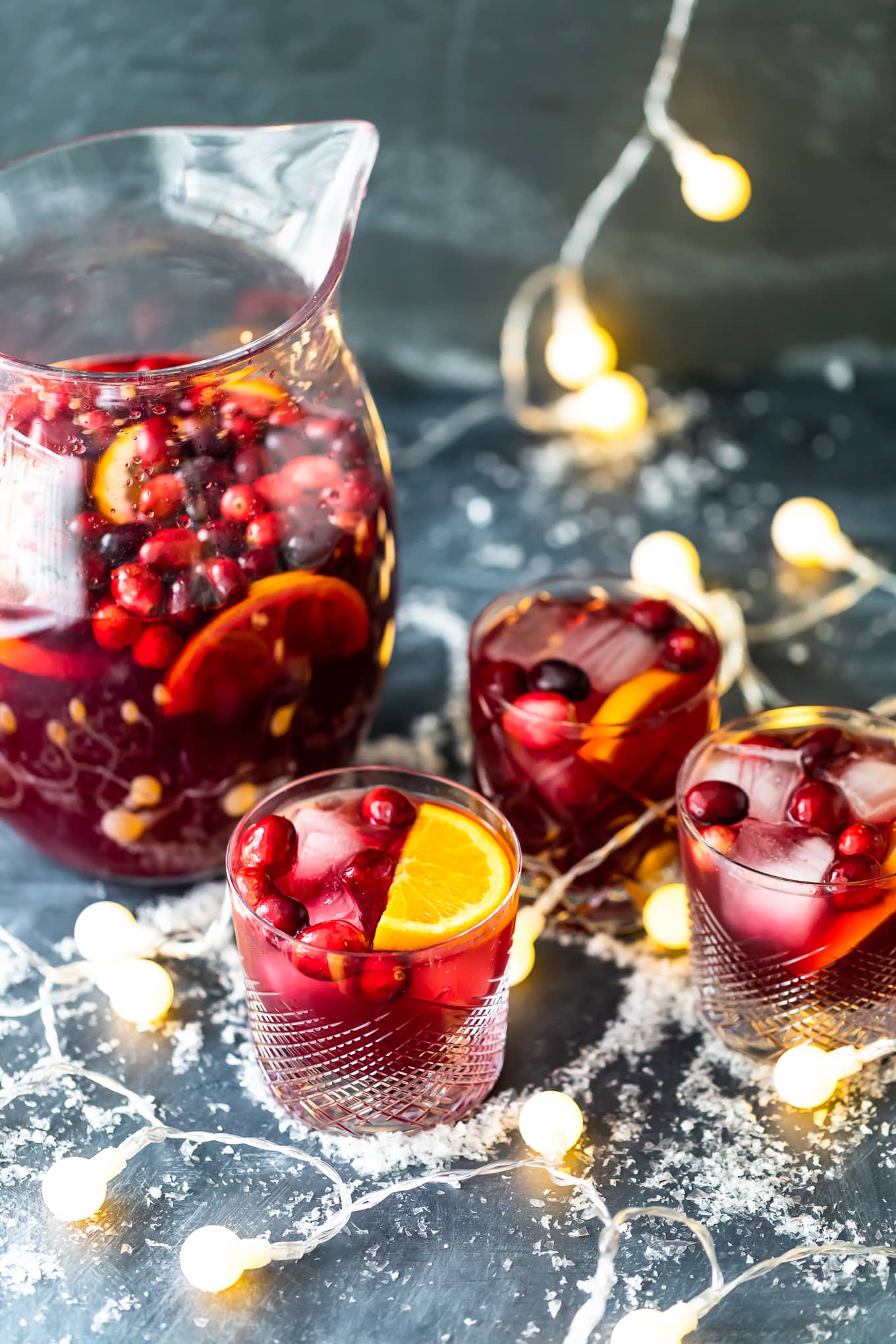 a pitcher of Christmas sangria next to three glasses of sangria