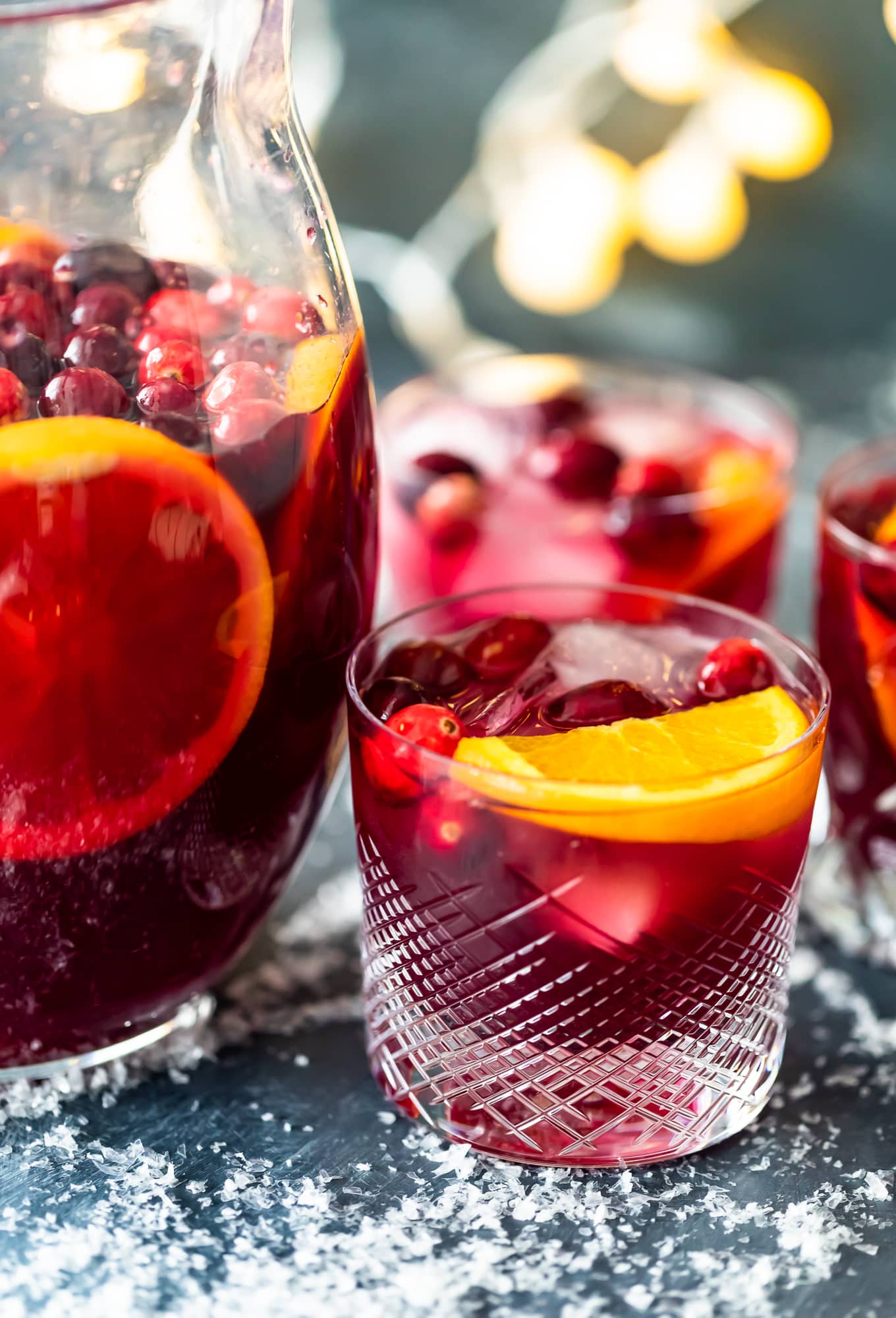 a pitcher of orange cranberry sangria next to glasses 