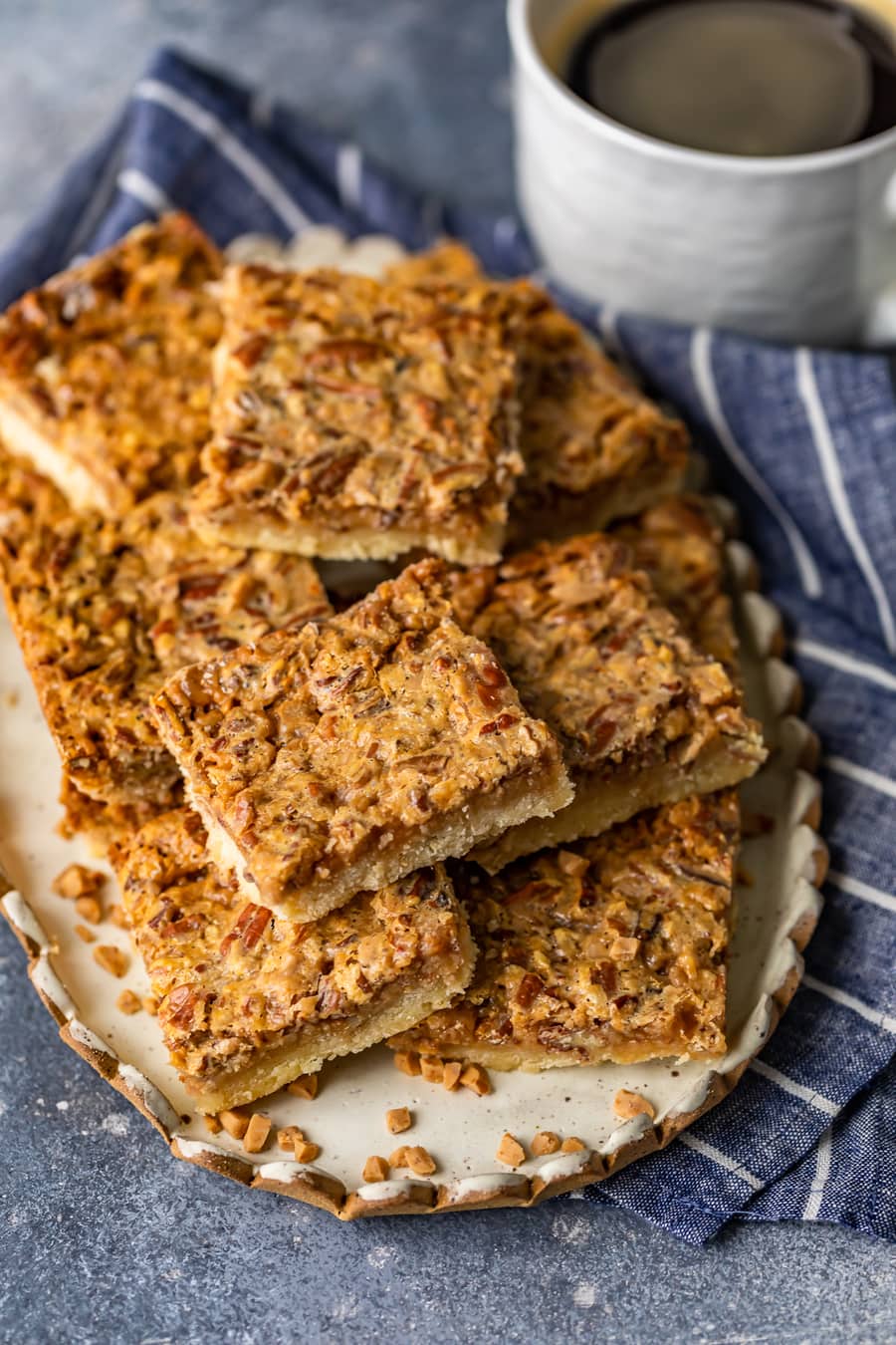 a plate of pecan bars sitting on a blue and white striped dish towel