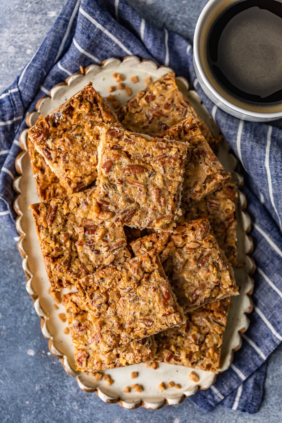 a serving plate filled with pecan bars, on a blue and white striped dish towel