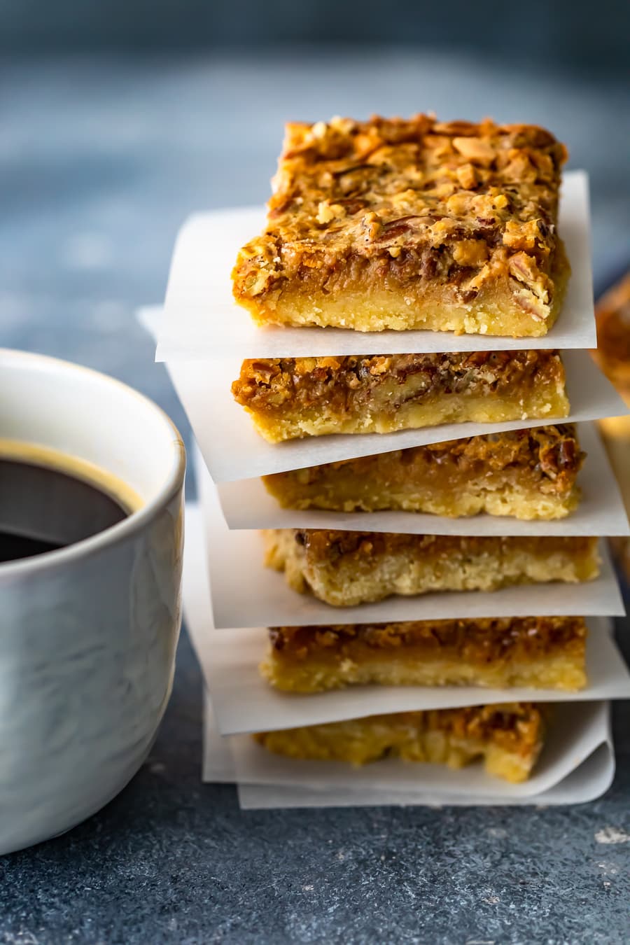 a stack of pecan pie bars with sheets of parchment paper between each one