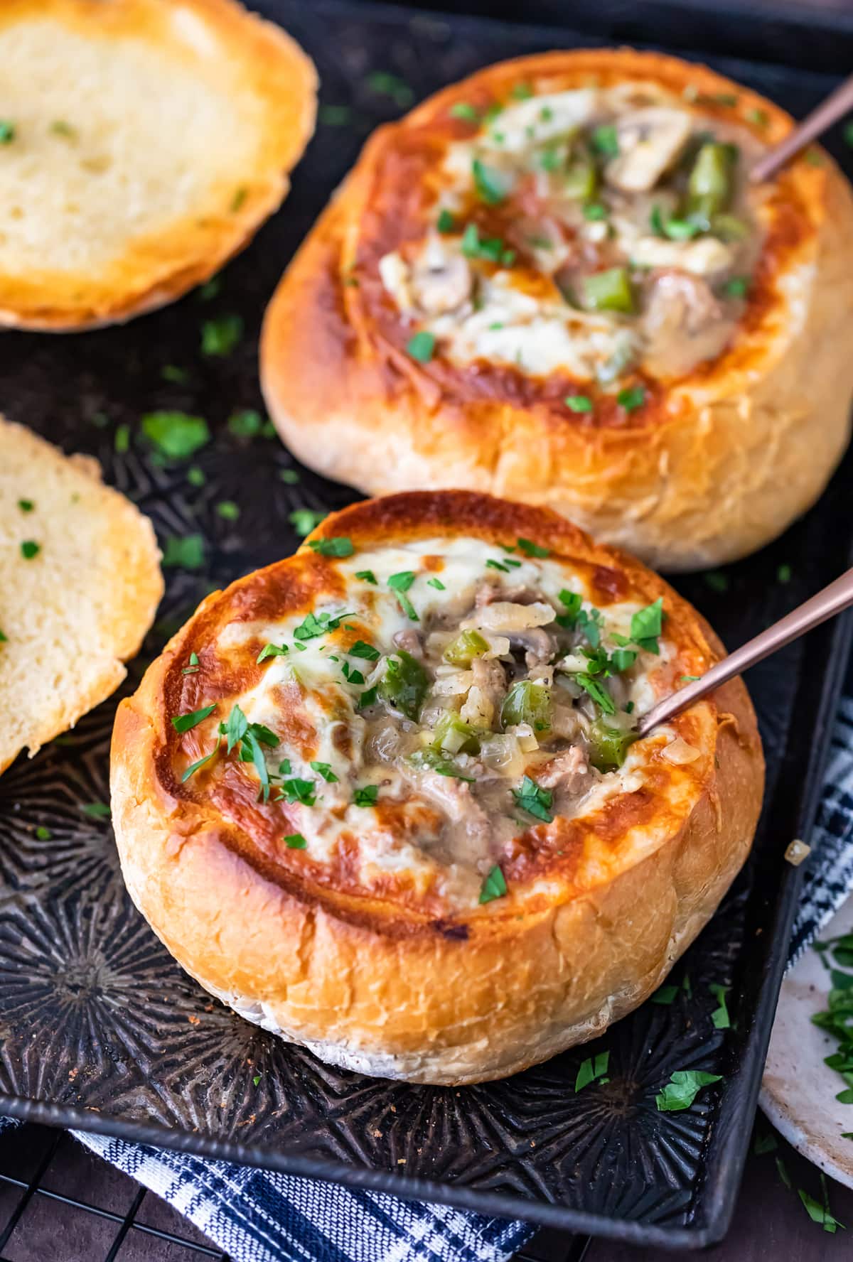 bread bowls filled with philly cheese steak soup, topped with cheese