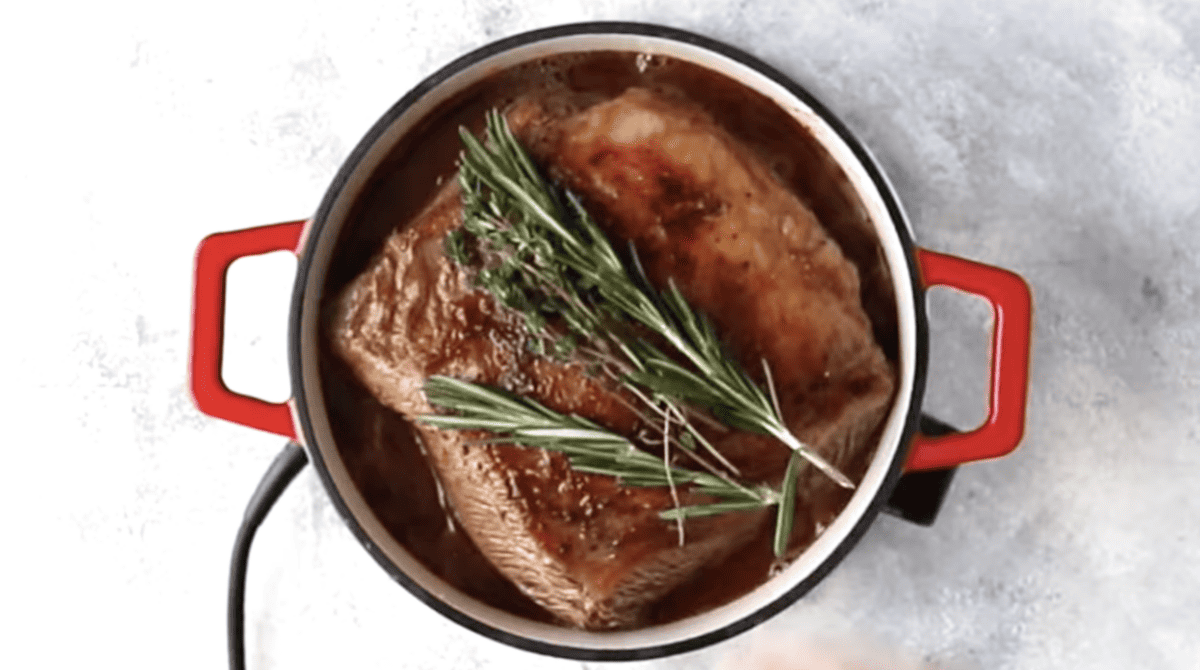 A pot with red wine and rosemary-infused meat stew.