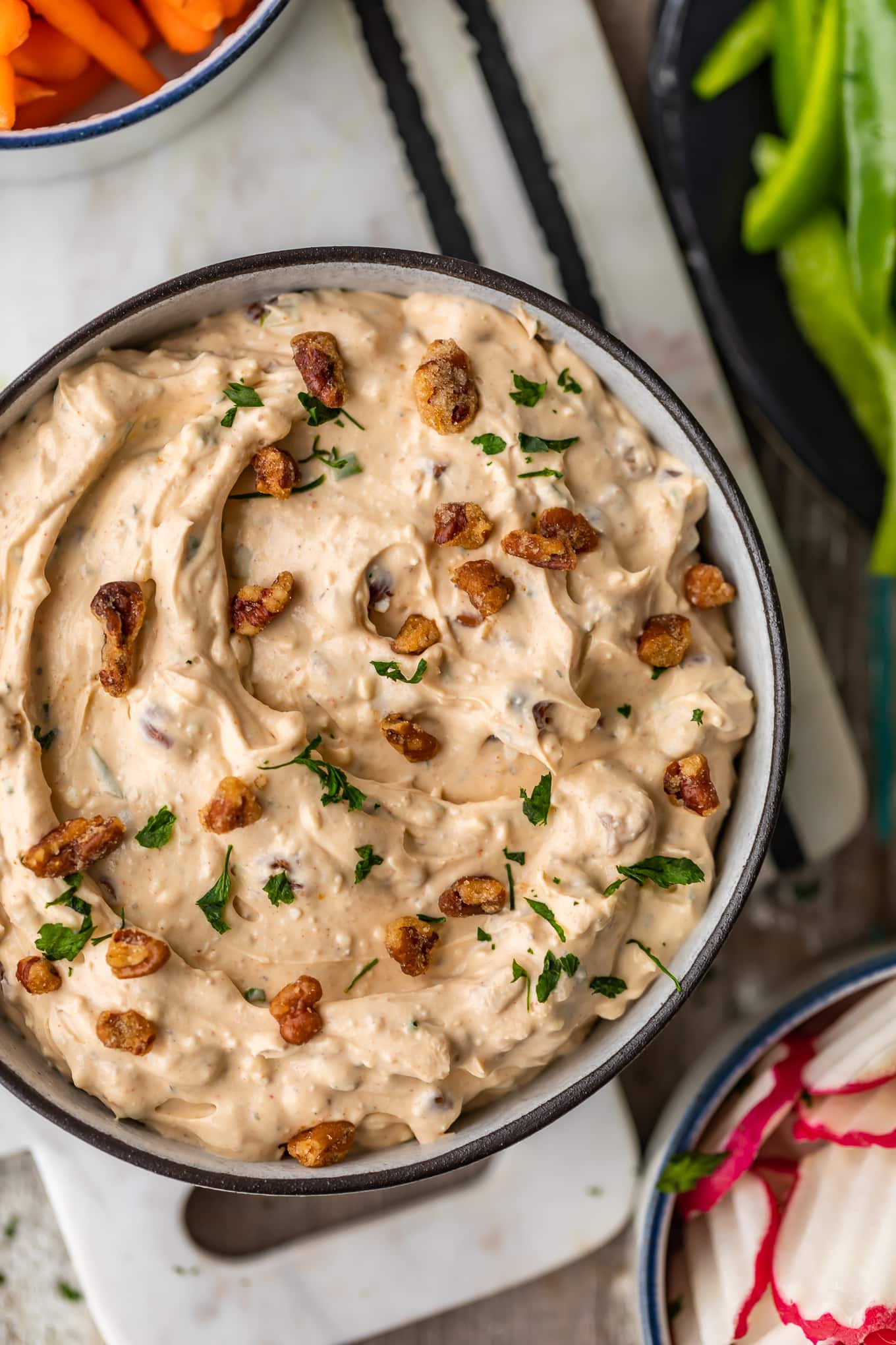 overhead view of a bowl of blue cheese dip topped with pecans and chives