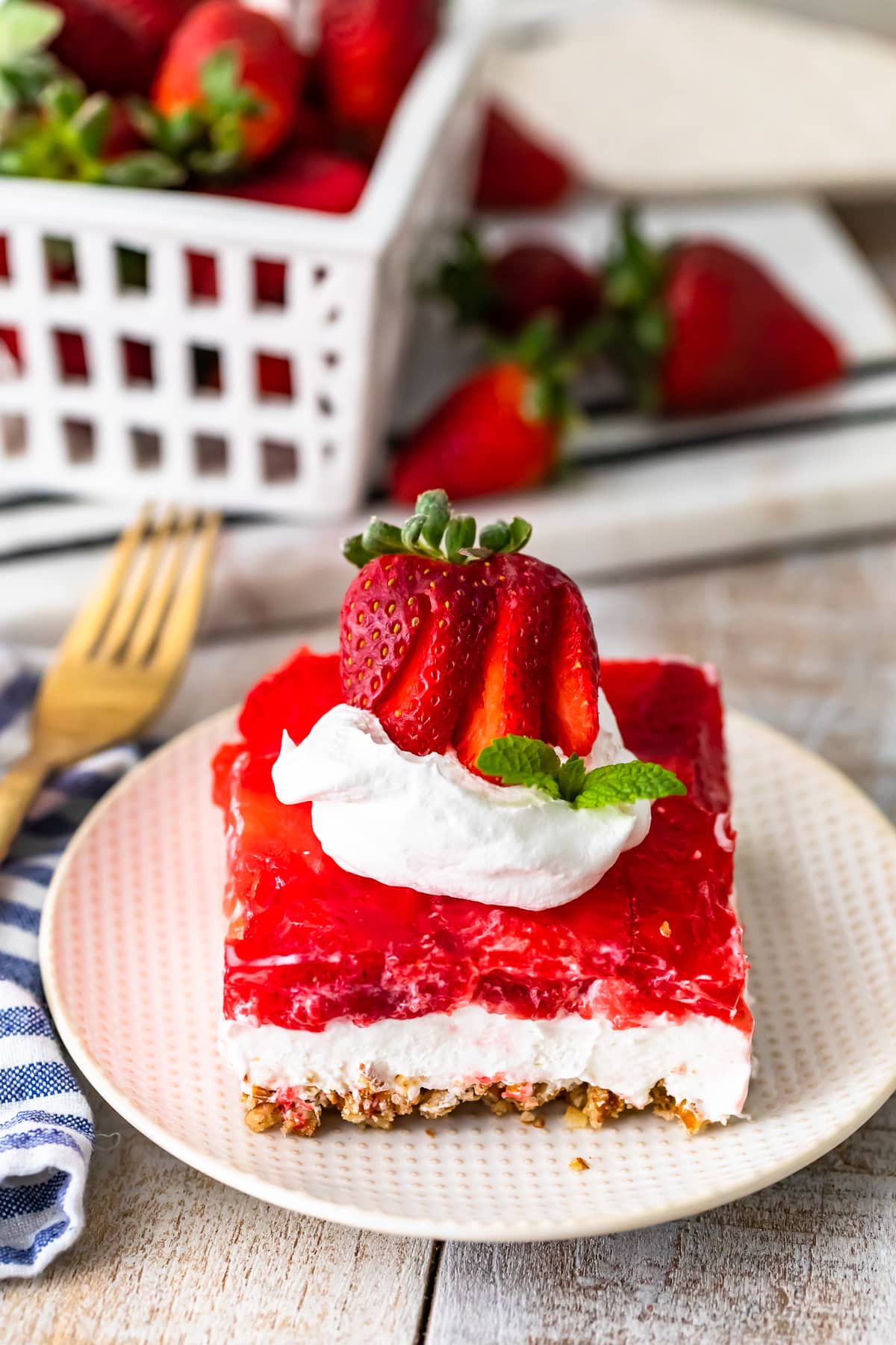 Strawberry Pretzel Salad on a plate in front of a basket of strawberries