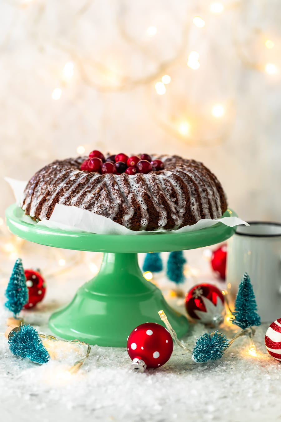gingerbread cake on a green cake stand, surrounded by small Christmas decorations