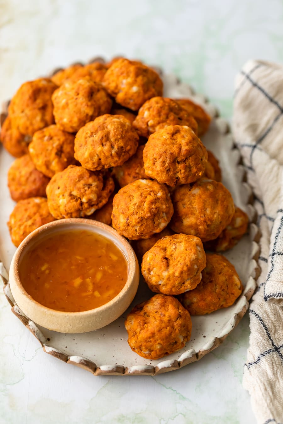 a plate of sweet potato sausage balls with a small bowl of marmalade dipping sauce