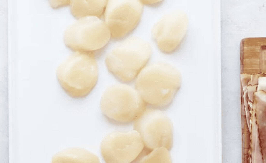 Scallops on a white cutting board.