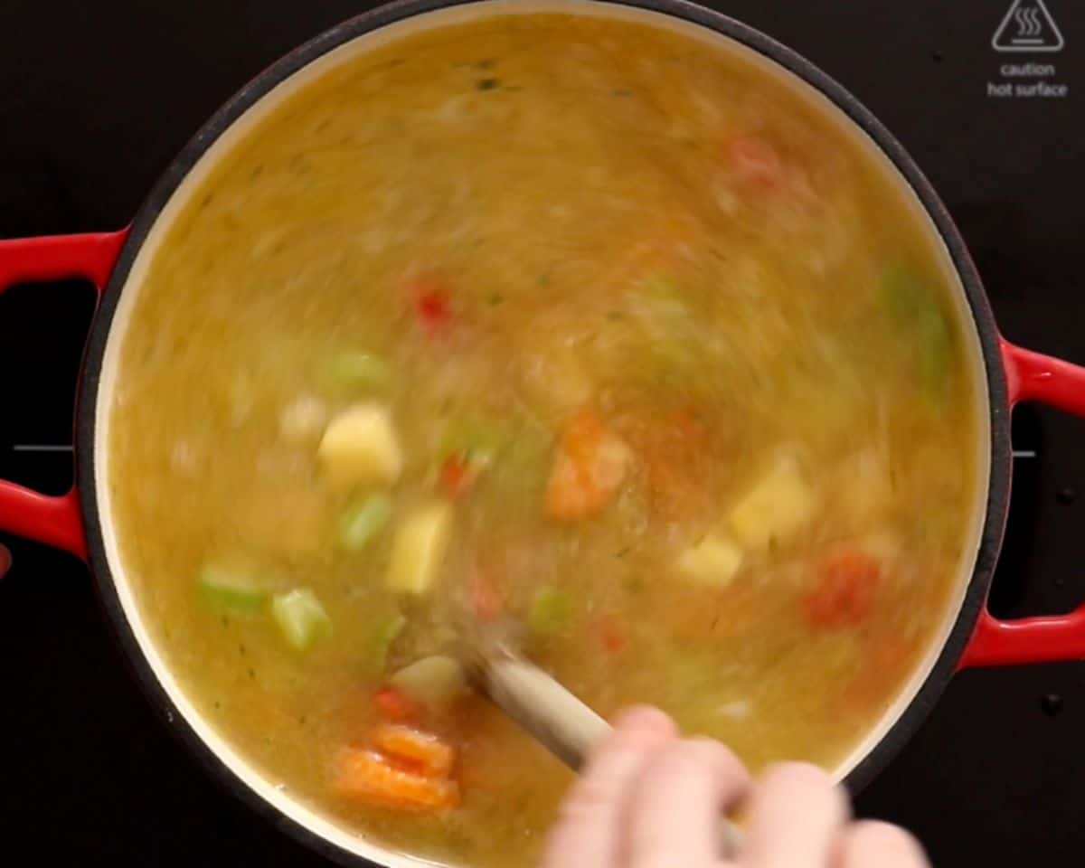 Simmering the soup and stirring with a spoon.