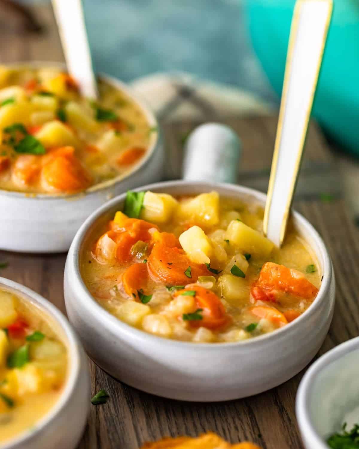 Bowls of cheesy potato soup with spoons in them.