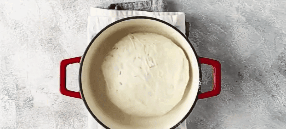 Dutch oven bread dough in a red Dutch oven.