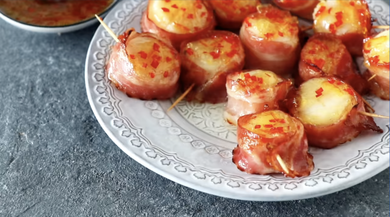 bacon wrapped scallops on a white plate.