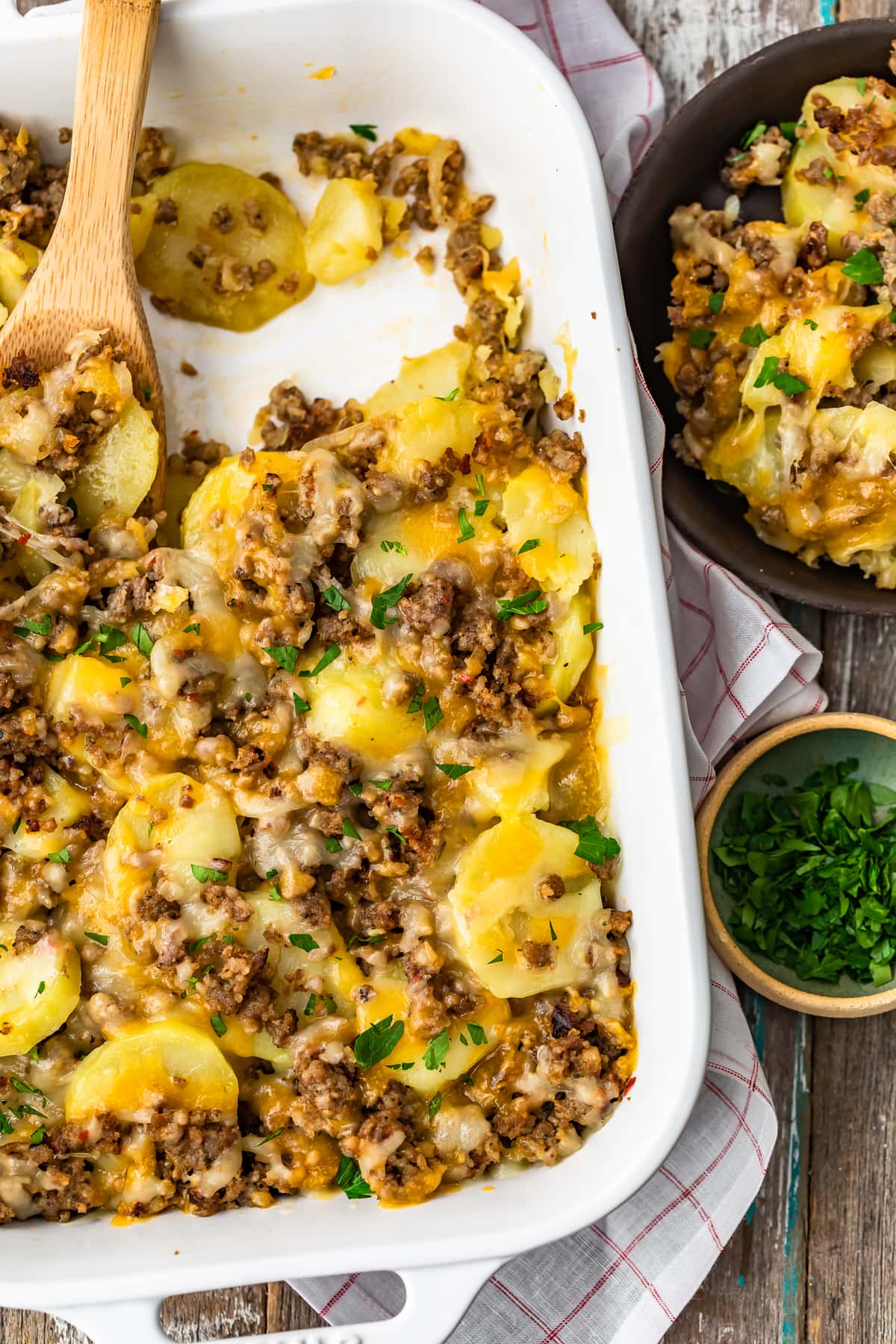 white dish filled with sausage and potatoes, next to a bowl of it