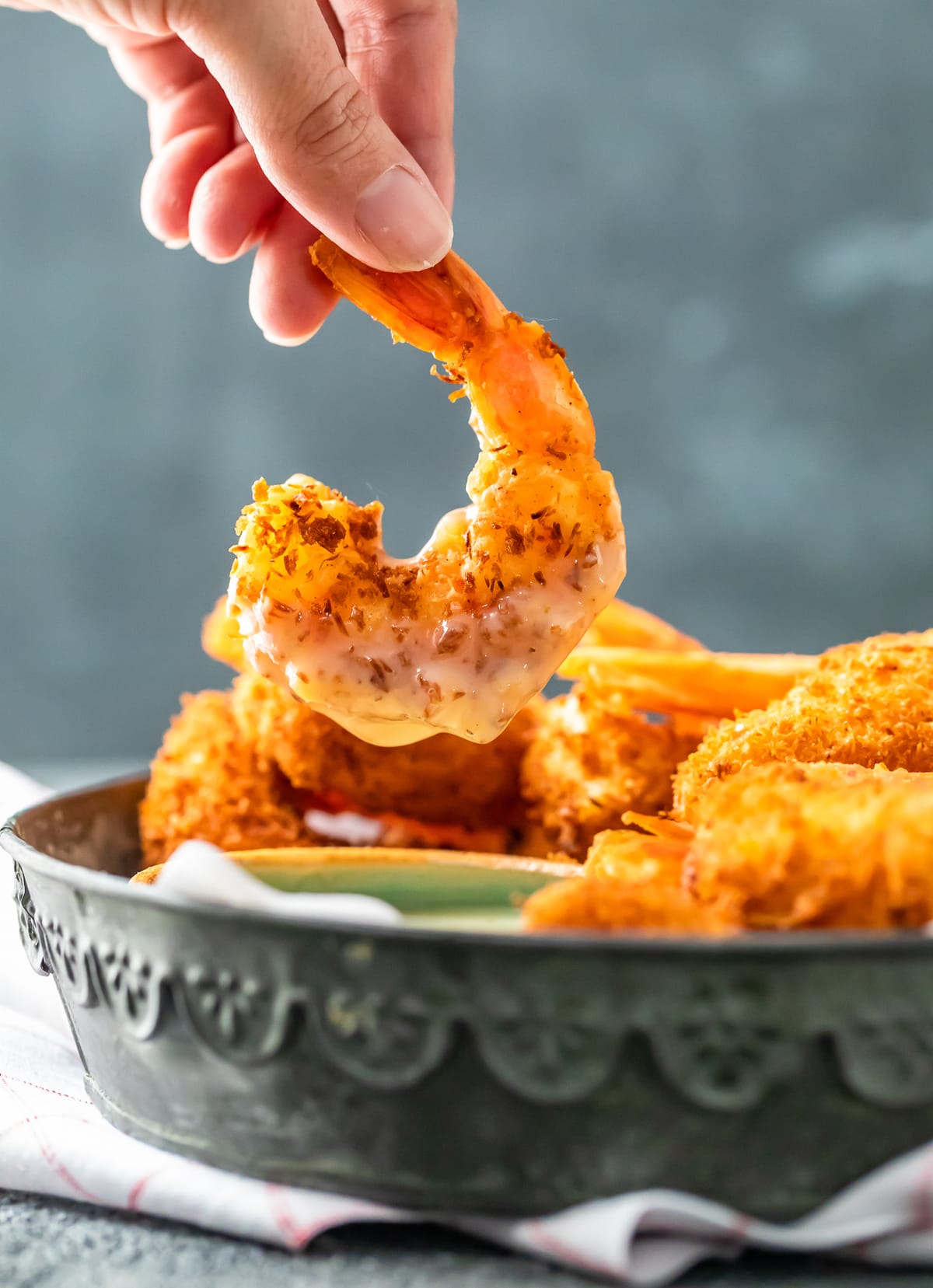 Coconut Shrimp is a crispy, crave-worthy appetizer that everyone will love. It's especially delicious when paired with the perfect coconut shrimp sauce: a Spicy Pina Colada Dipping Sauce! The two go hand in hand, a match made in heaven. And this coconut shrimp recipe is just as good as a main dish as it is as a party appetizer! a coconut shrimp dipped in pina colada sauce.
