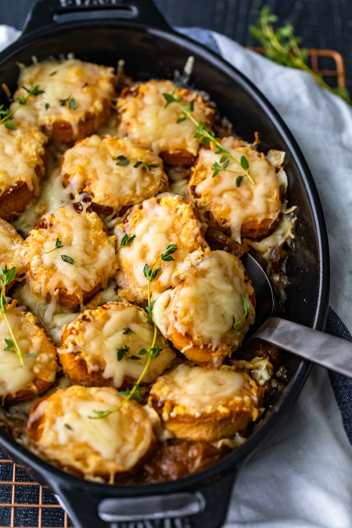 french onion soup casserole in a black dish with a serving spoon