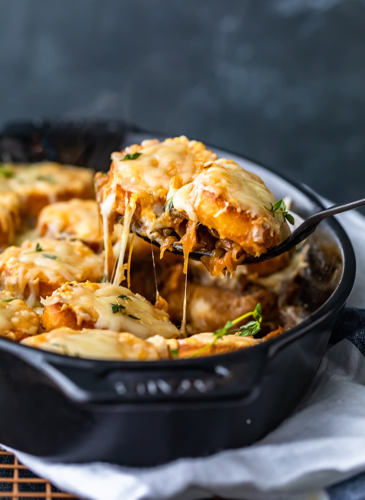 scooping a piece of french onion casserole out of a black dish