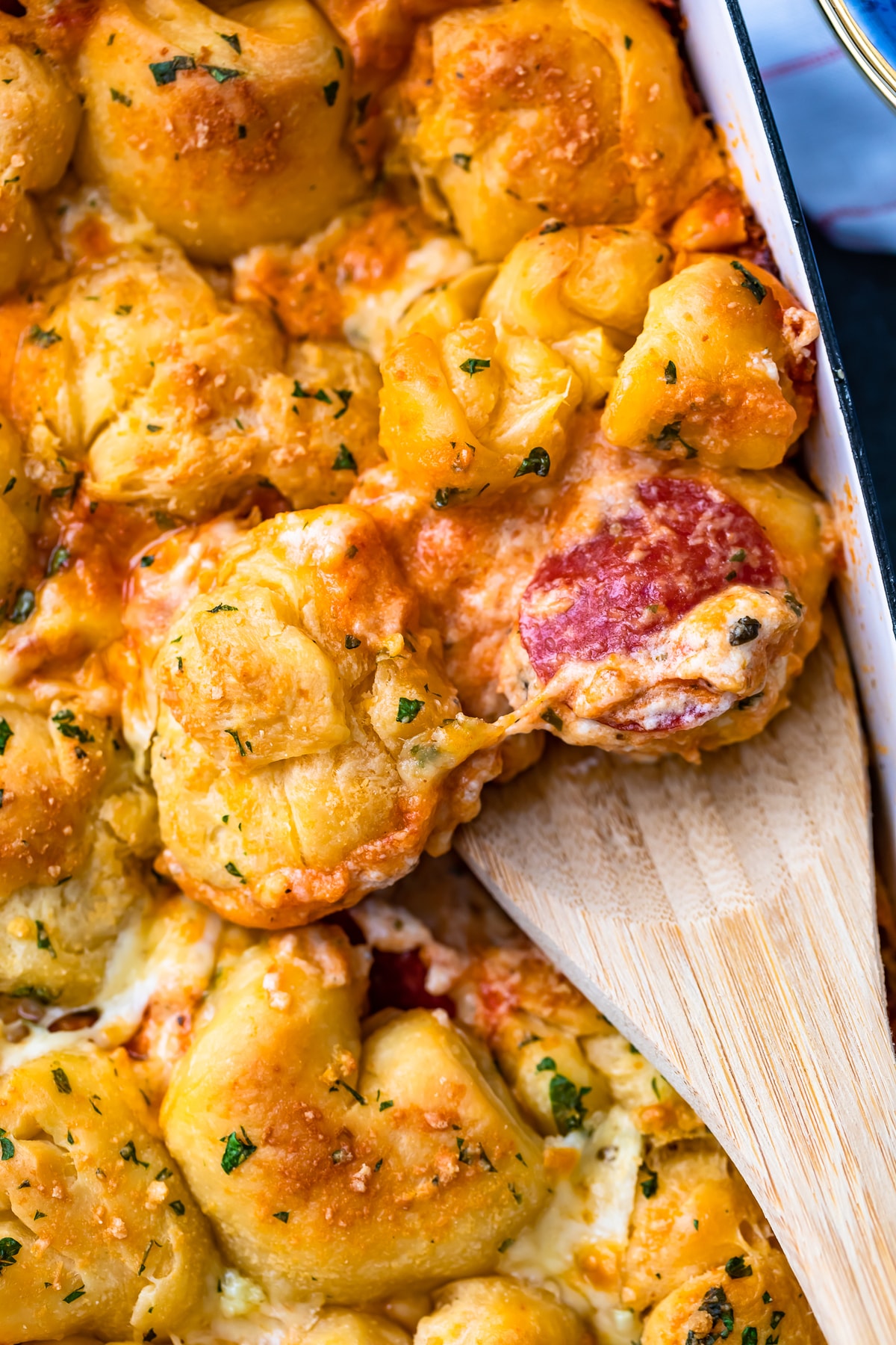 wooden spoon digging into a pizza casserole