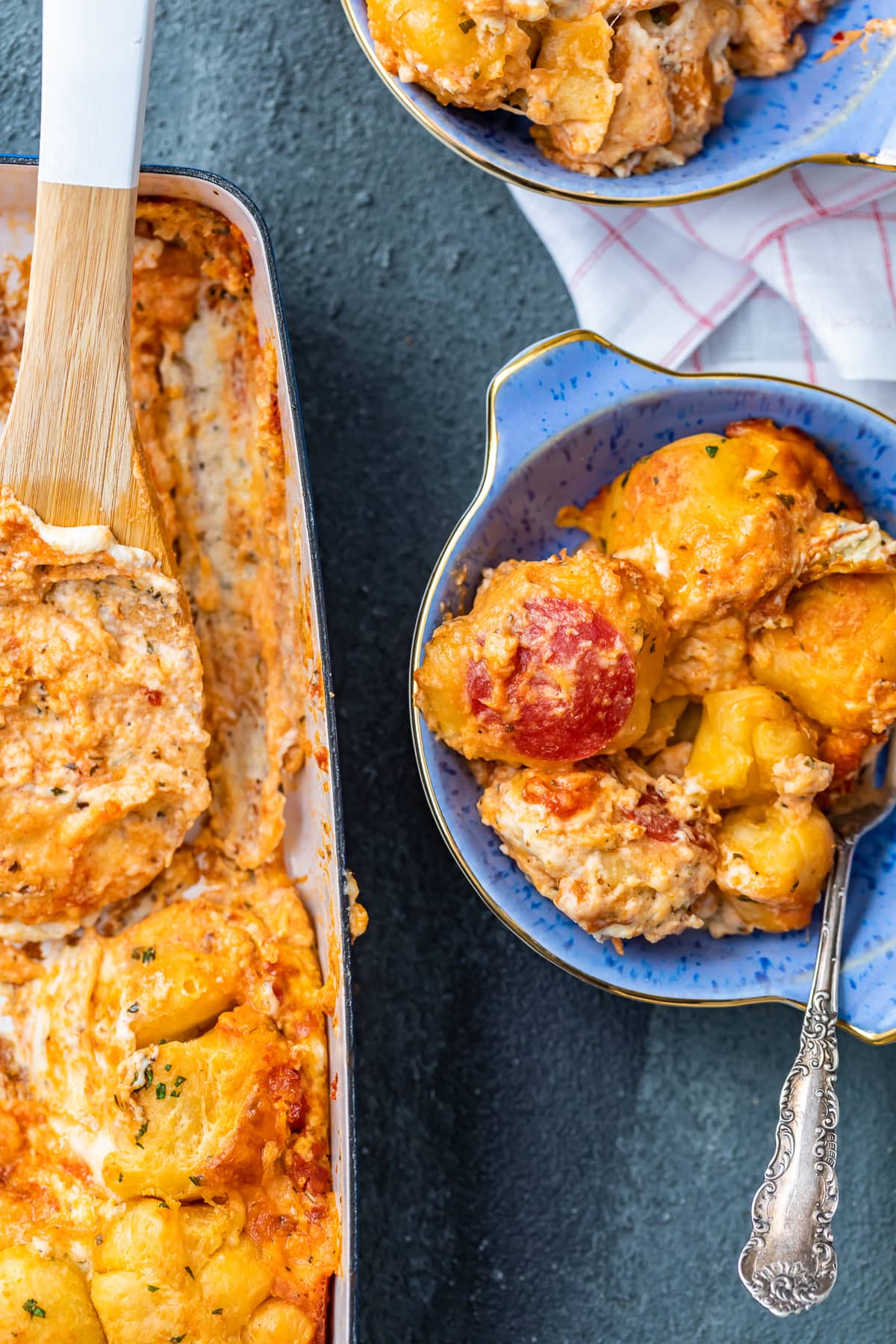 a pizza casserole next to a bowl with a serving of the casserole in it