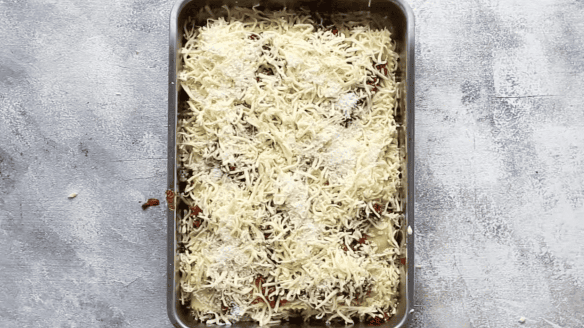 A baking dish with lasagna and cheese in it.