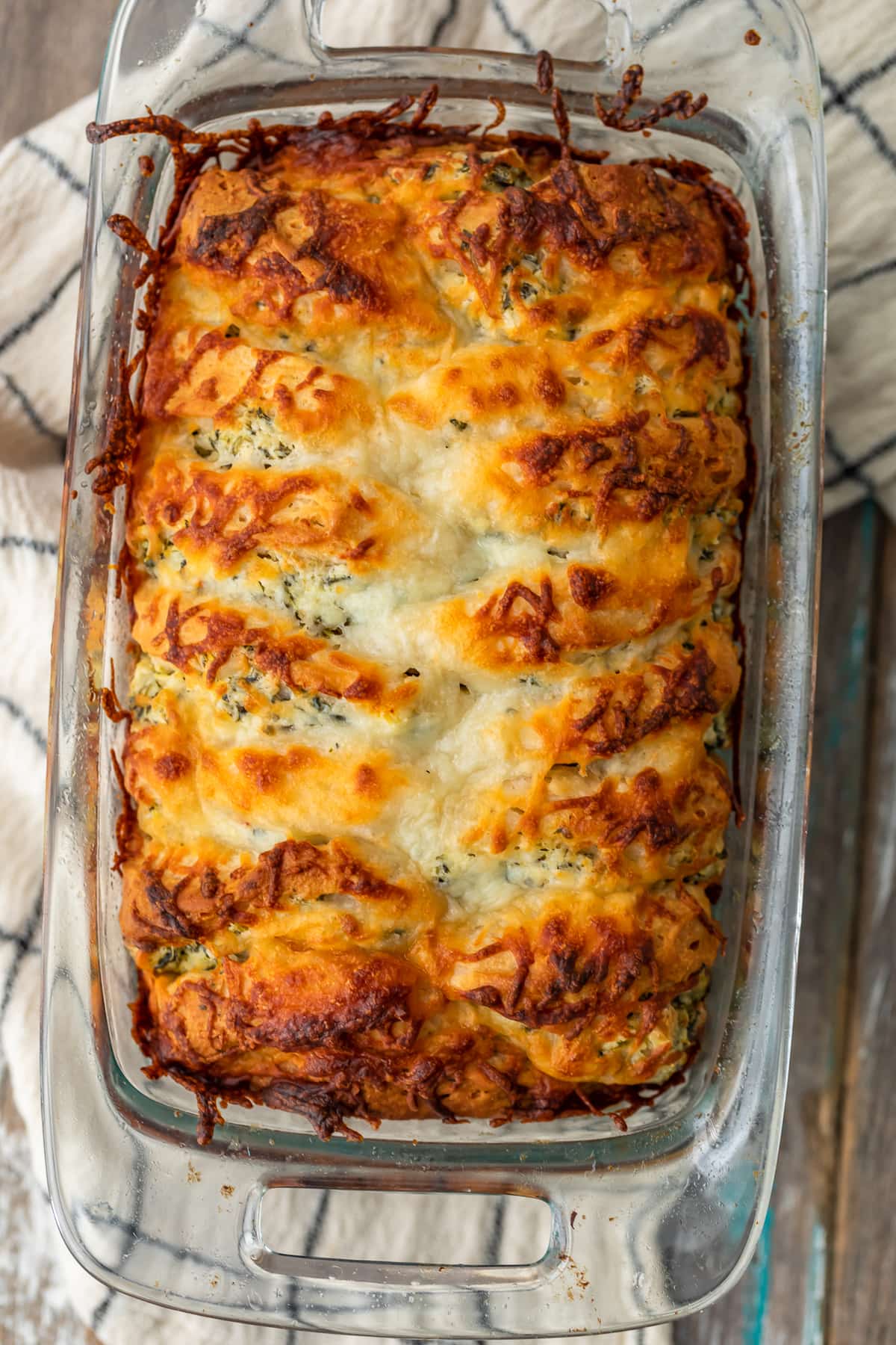 a clear glass loaf pan filled with cheesy spinach artichoke dip bread