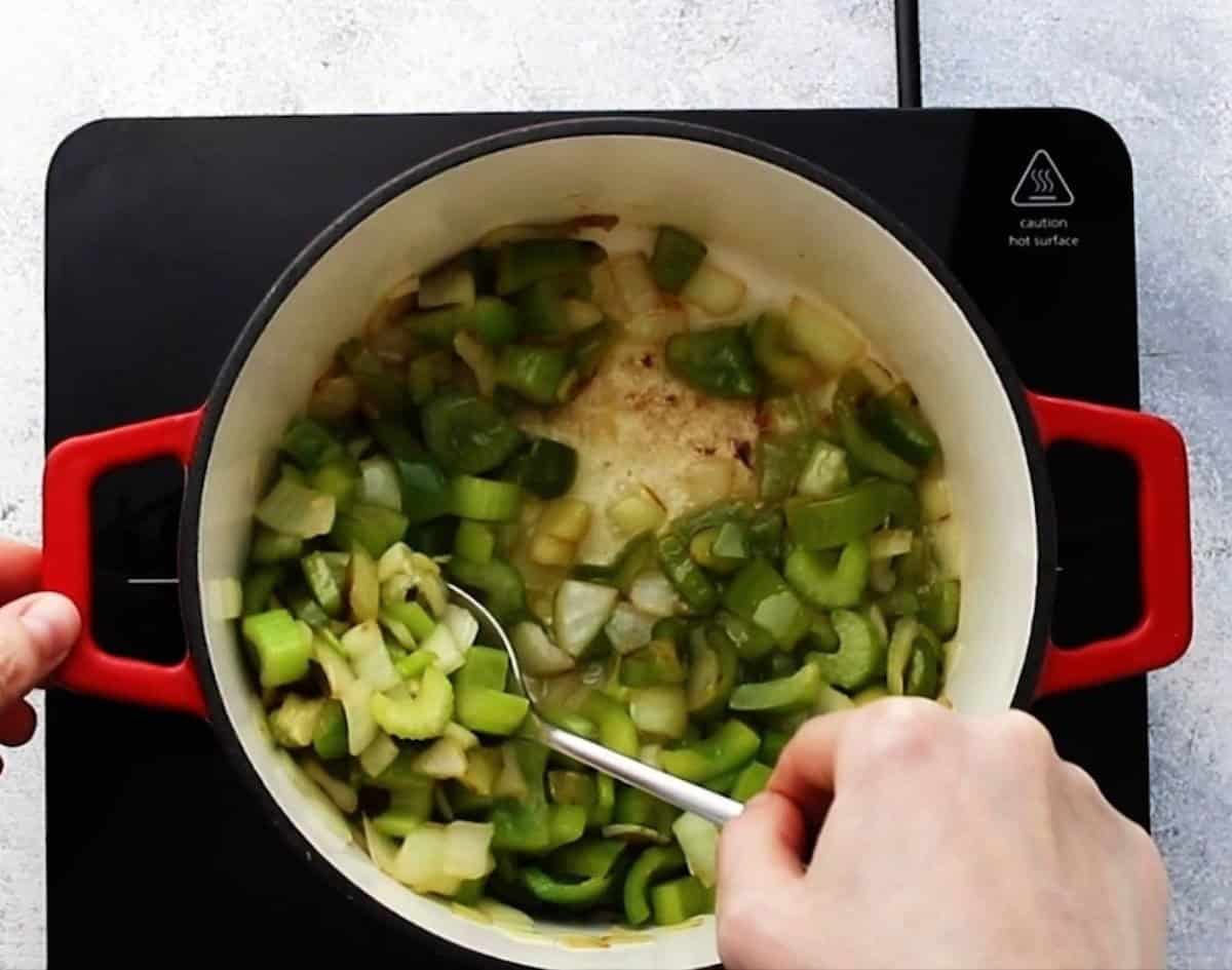 Cooking onions and green peppers in a pot.