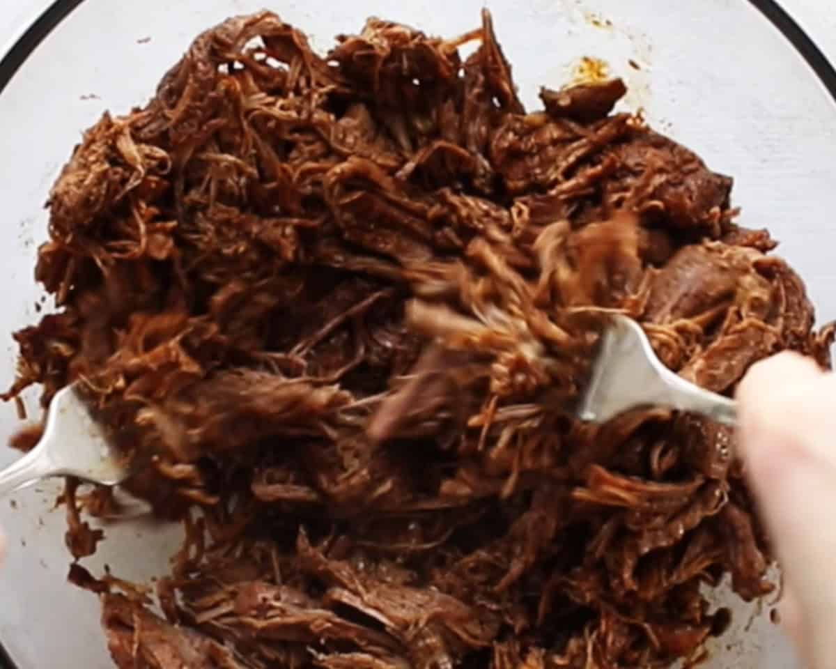 Shredding the beef with two forks.