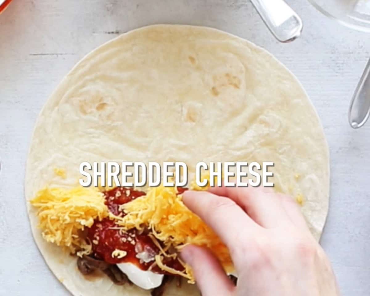 Layering a tortilla with beef, sauce, sour cream, and cheese.
