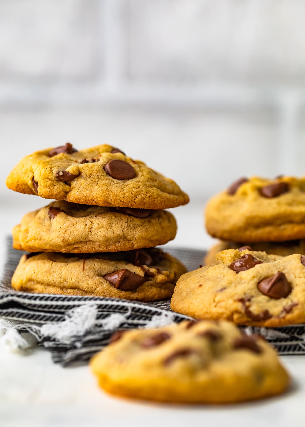 soft and chewy chocolate chip cookies stacked on a dish towel