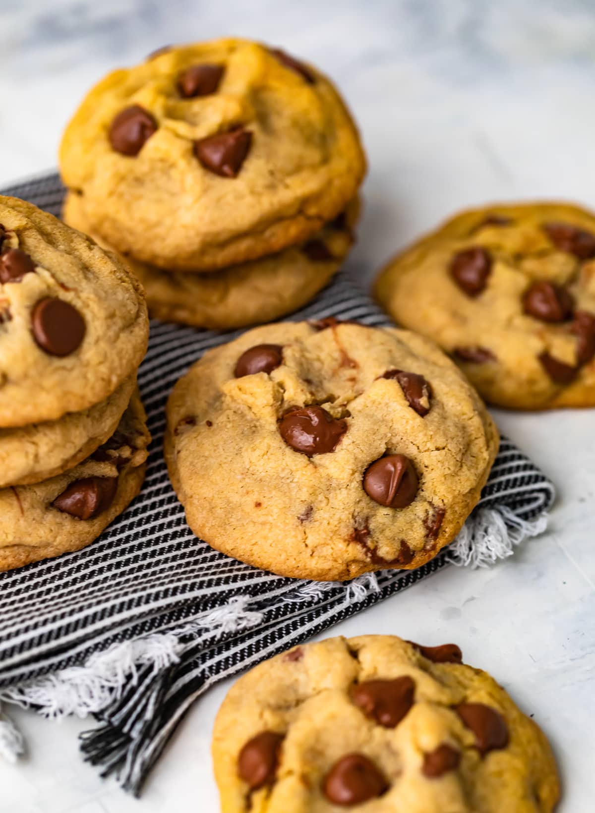 soft and chewy chocolate chip cookies stacked on a dish towel