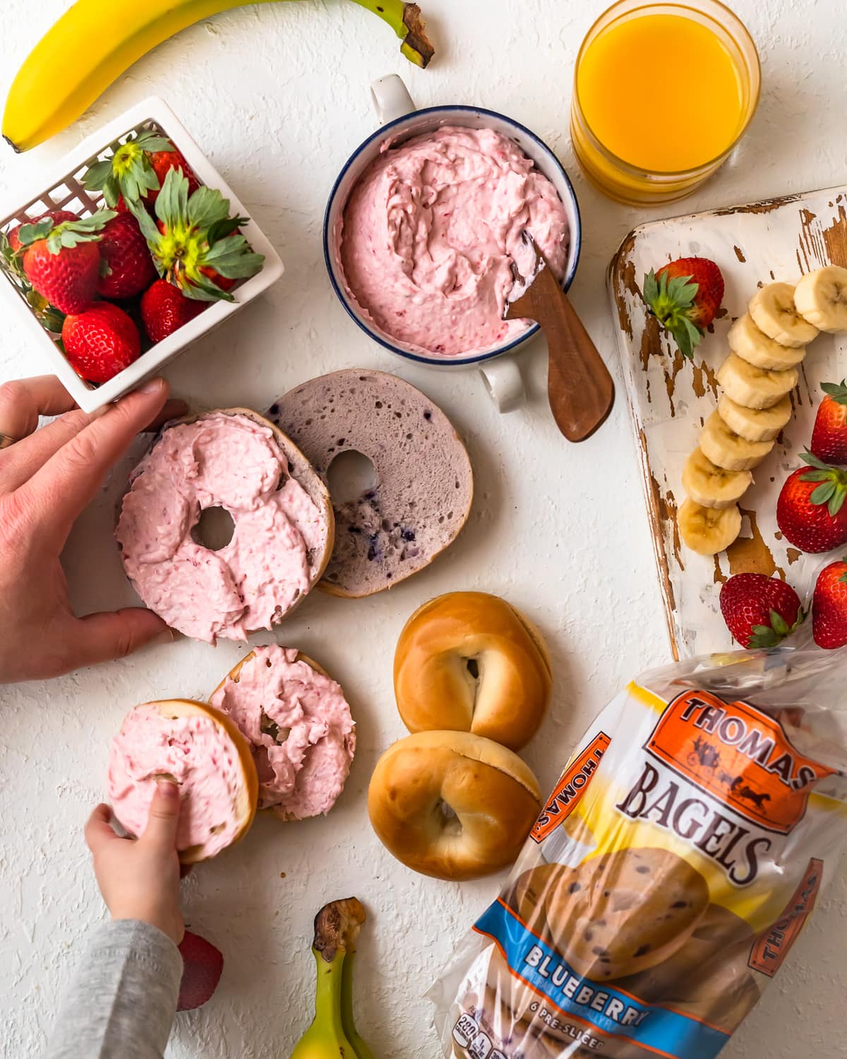 bagels, cream cheese, and fruit arranged on a table in a breakfast scene