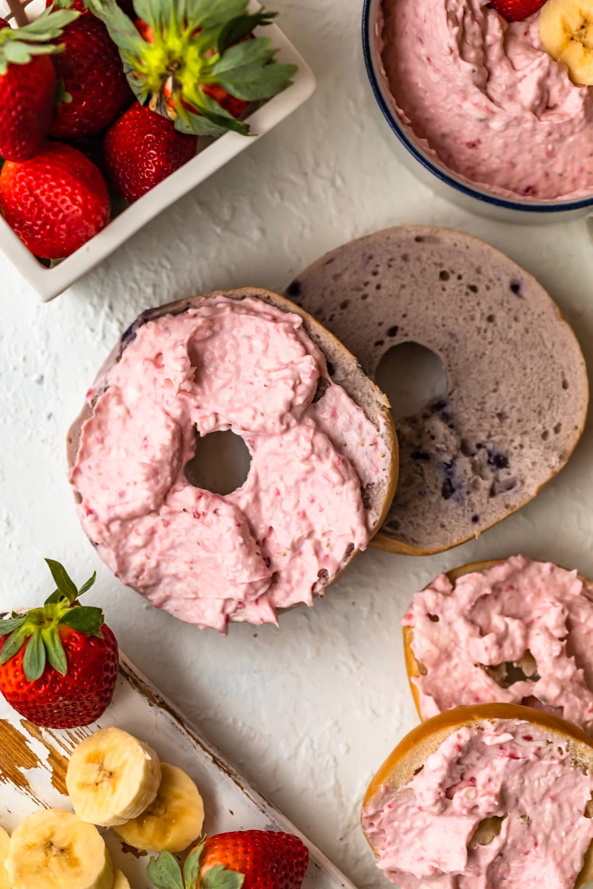 a blueberry bagel sliced in half, one half topped with strawberry cream cheese