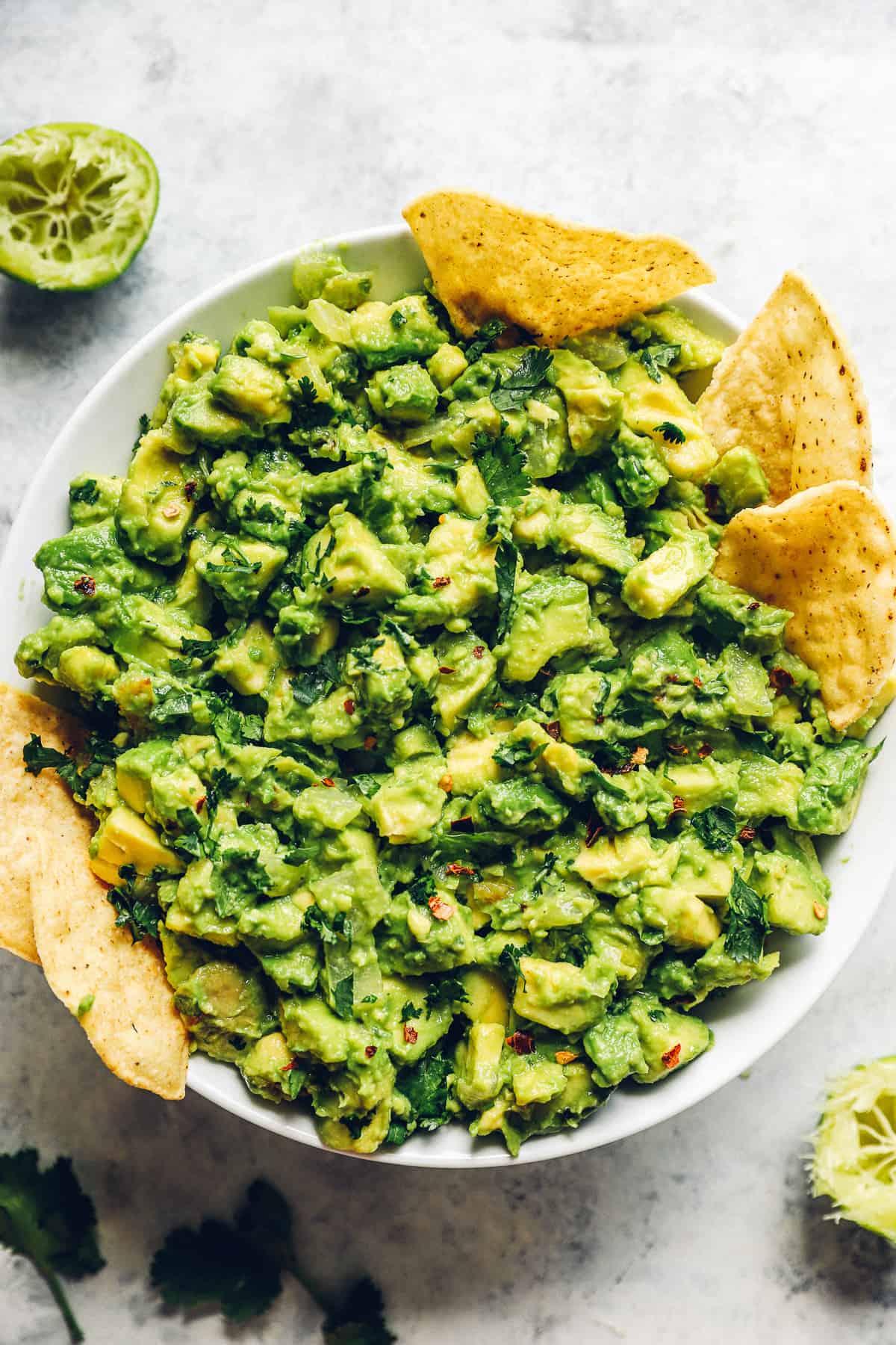 Large white bowl filled with margarita guacamole and tortilla chips.