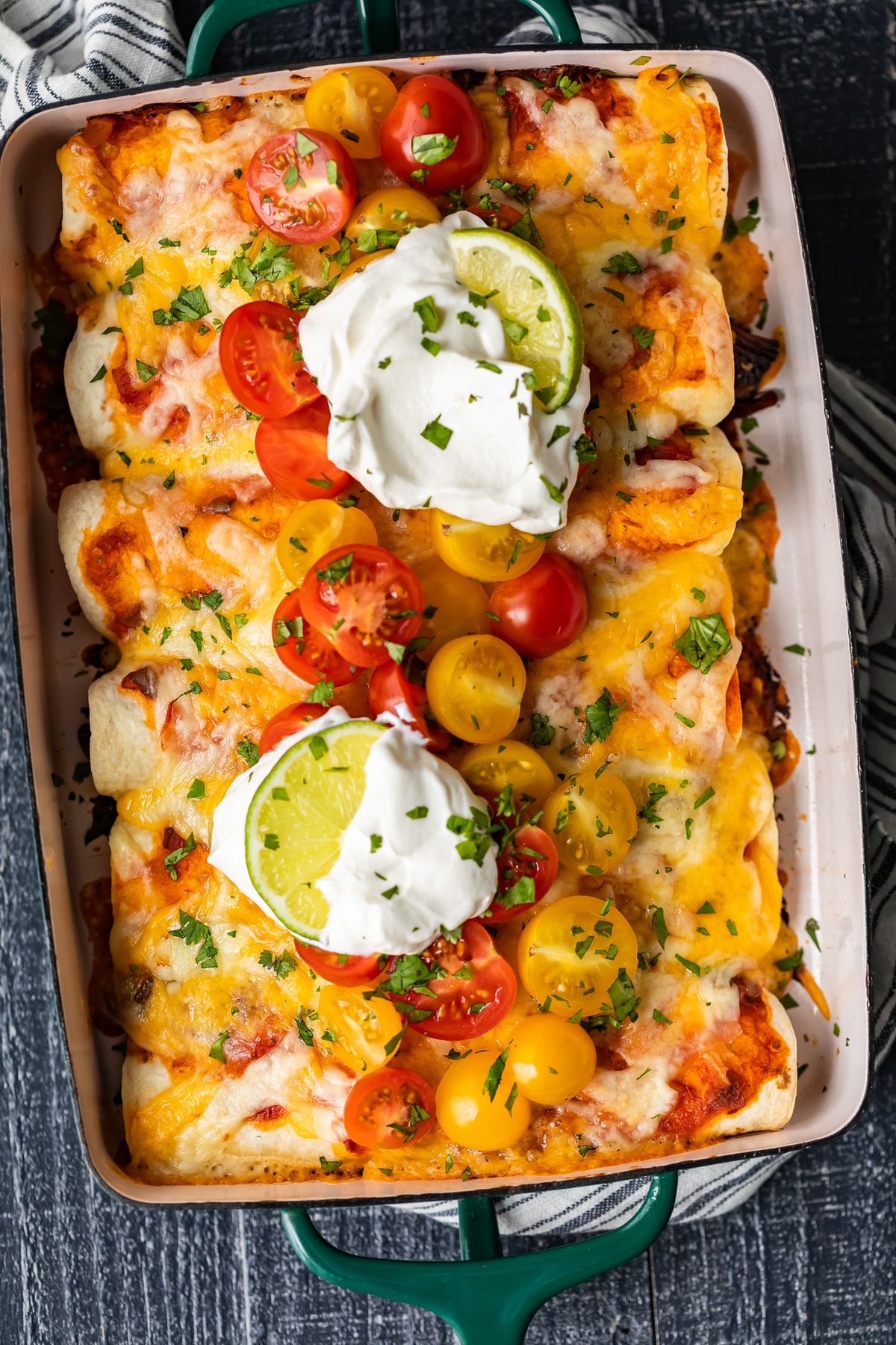 shredded beef enchiladas topped with sour cream, tomatoes, cheese, and cilantro